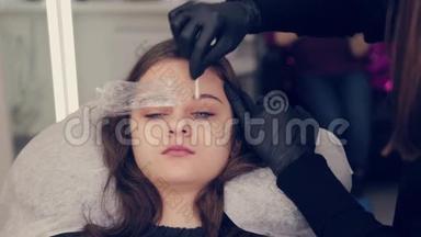 在一家美容院，专业的眉毛大师将胶卷从眉毛上取下，并去除眉毛上的液体